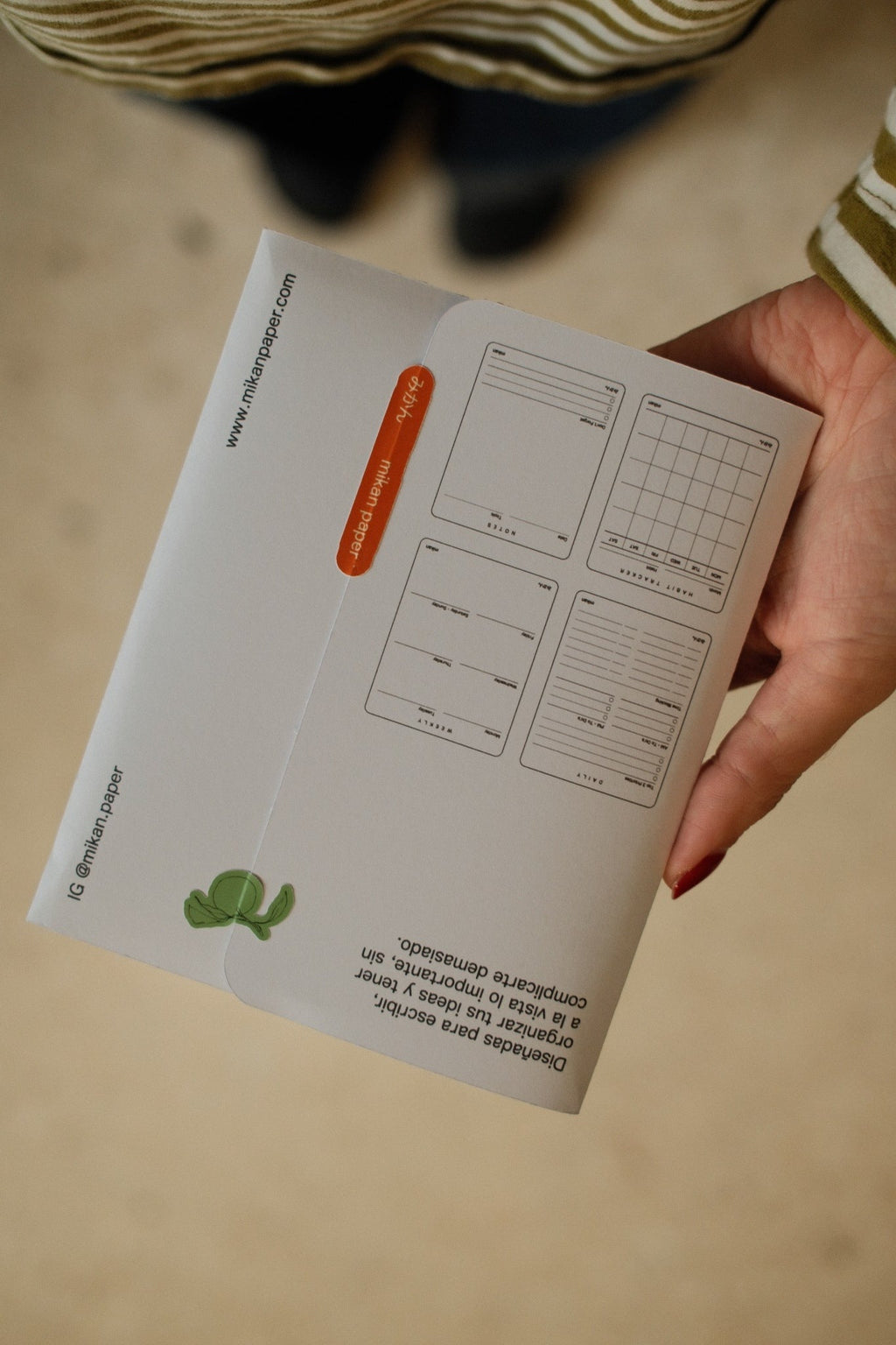 Reverso del empaque Mikan sostenido en mano, fotografía vertical corregida